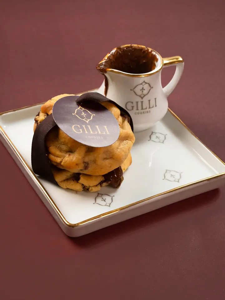 Dois cookies empilhados com a etiqueta Gilli e uma jarrinha de chocolate