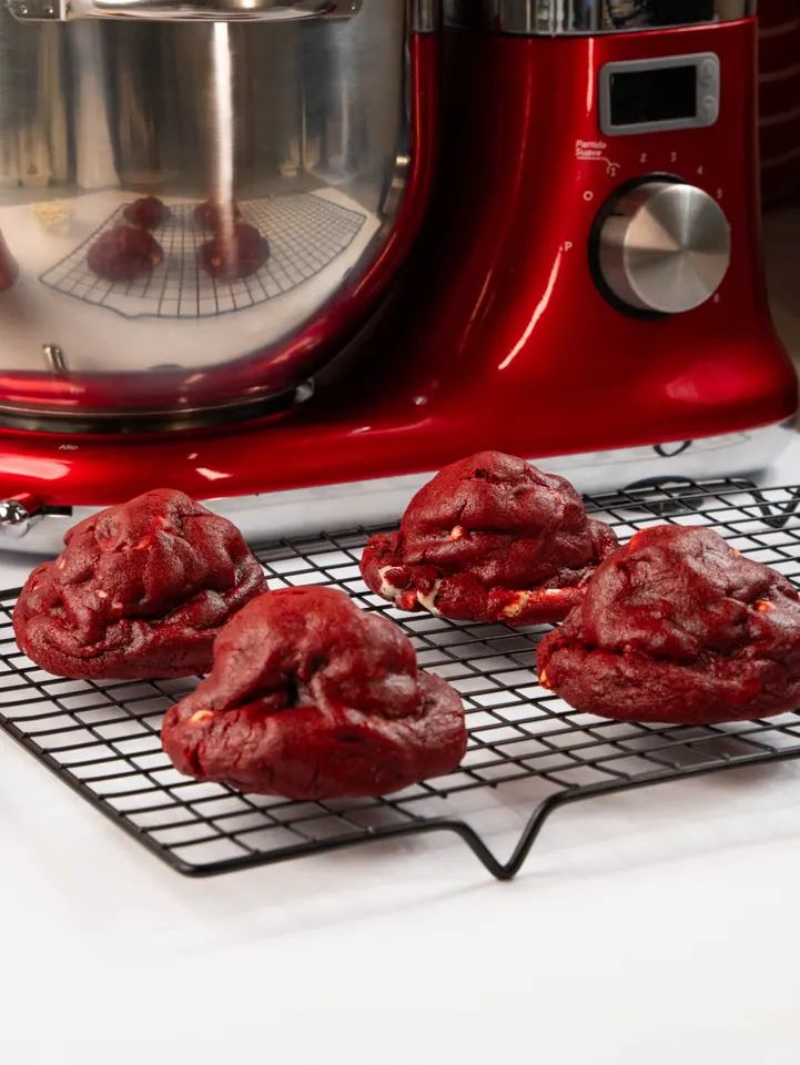 Cookies red velvet esfriando na grade em frente à batedeira vermelha