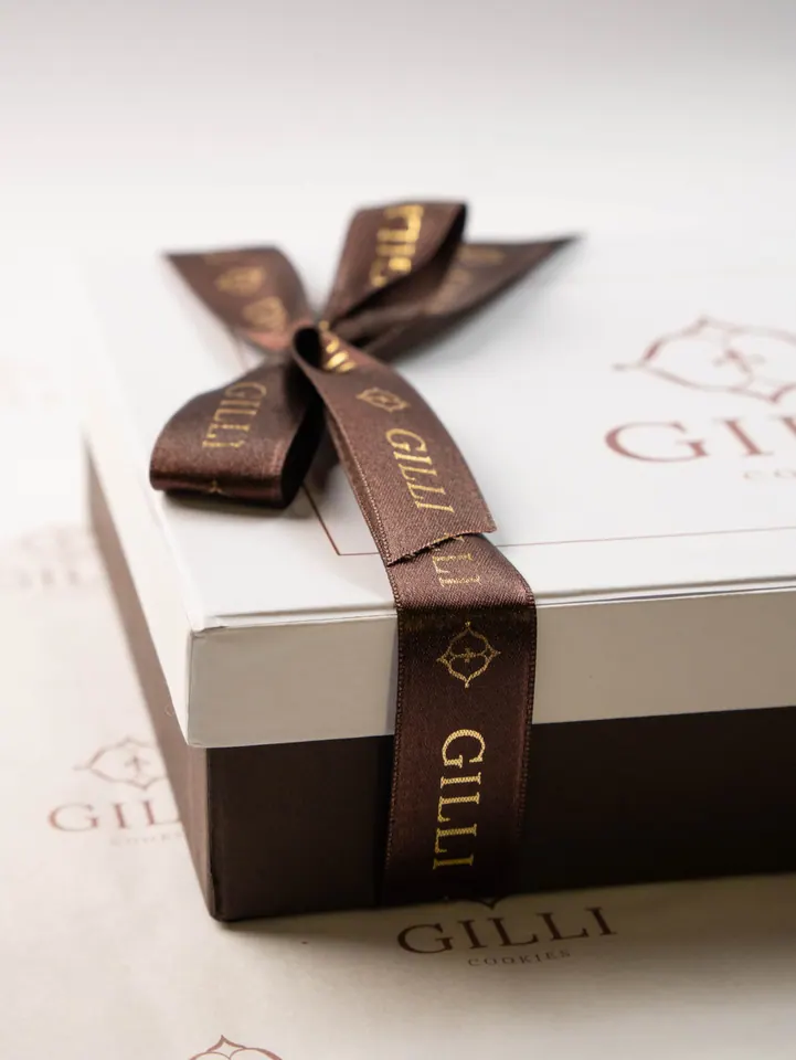 Detalhe do laço de cetim marrom com a marca Gilli em dourado