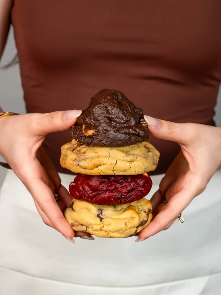 Pilha de quatro cookies segurada com as duas mãos